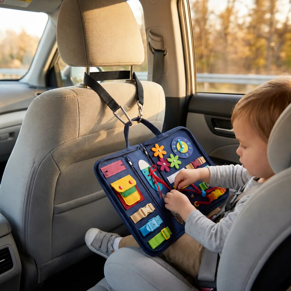 The busy board attached to the headrest with its black travel strap, in the car