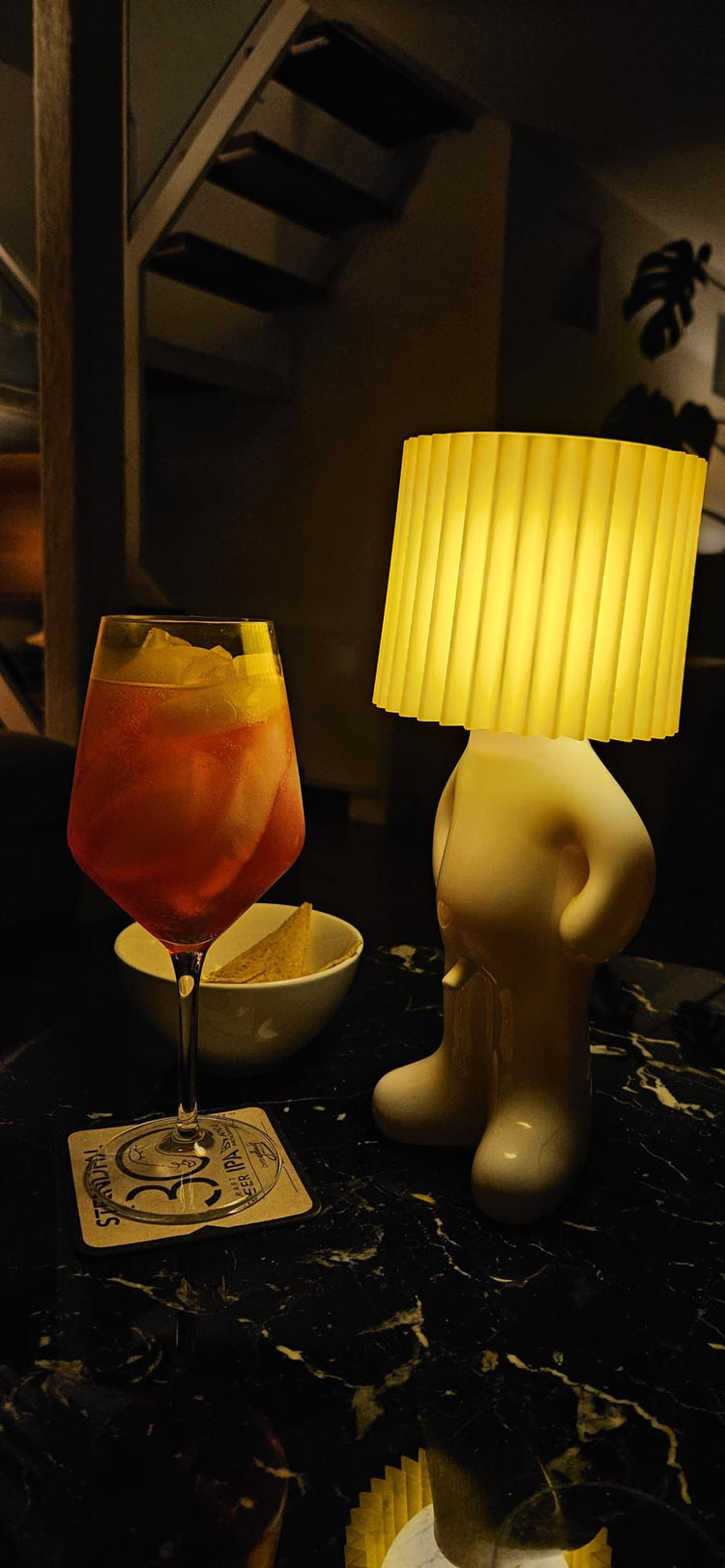 Leo Lamp yellow next to an evening drink