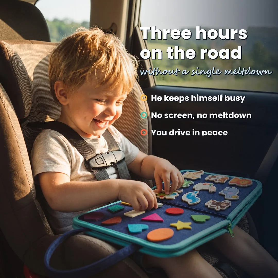 Child laughing in his car seat with the blue Lysby busy board