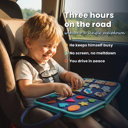 Child laughing in his car seat with the blue Lysby busy board